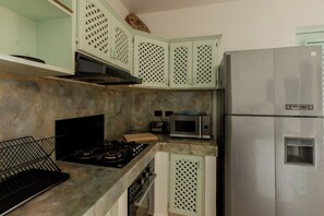 A kitchen with a gas stove, a microwave, a refrigerator, and a water dispenser. - Bamboo House, Oceanfront, Las Terrenas, Punta Popi. Comfort, convenience, and magic. (Las Terrenas)