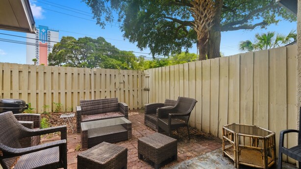 An outdoor patio with wicker furniture, a barbecue grill, and a wooden fence. - Island Breeze at Islander Cay (Myrtle Beach)