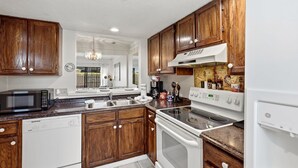 A kitchen with wooden cabinets, a microwave, a dishwasher, a stove, and a sink. - Island Breeze at Islander Cay (Myrtle Beach)