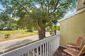 Parvekkeessa on valkoinen kaide, palmu ja kaksi rottingista tuolia.