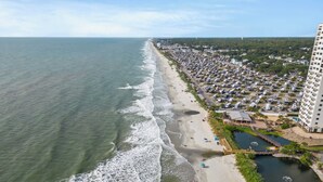 A coastal area with a beach, a parking lot, and a large building. - Myrtle Beach Resort Ocean View Condo (Myrtle Beach)