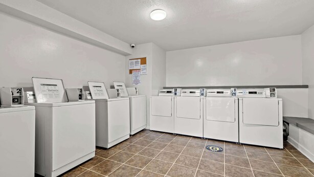 A laundry facility with multiple washing machines and dryers, numbered from 2 to 9, and a security camera on the ceiling. - Myrtle Beach Resort Ocean View Condo (Myrtle Beach)
