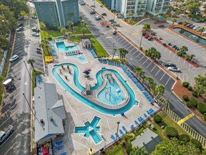 An aerial view of a hotel with multiple swimming pools, a parking lot, and surrounding buildings. - Myrtle Beach Resort Ocean View Condo (Myrtle Beach)