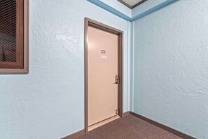Une porte avec un numéro, un mur à texture et un coin orné d’une bordure bleue.