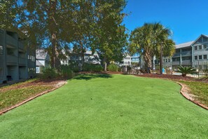 A well-maintained lawn with a clear sky, surrounded by multi-story buildings with balconies. - Myrtle Beach Resort Ocean View Condo (Myrtle Beach)