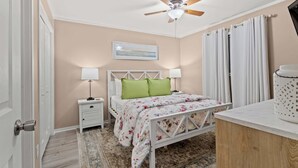 A bedroom with a bed, nightstands, a ceiling fan, a painting, and a window with curtains. - Myrtle Beach Resort Ocean View Condo (Myrtle Beach)