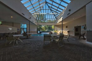 An indoor swimming pool area with a glass ceiling, multiple seating areas, and a pool table. - Myrtle Beach Resort Ocean View Condo (Myrtle Beach)