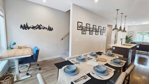 A modern dining area with a wooden table set for four, a blue chair, and a staircase leading to another level. - Pet-Friendly Panorama Escape / Hot Tub / Sleeps 10 (Panorama)