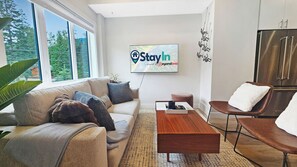 Ein modernes Wohnzimmer mit Sofa, Couchtisch und Fernseher, der 'Stay In' anzeigt.