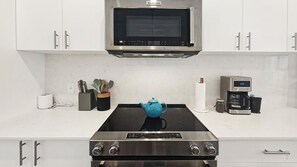 A kitchen with a stove, microwave, coffee maker, and utensils. - Pet-Friendly Panorama Escape / Hot Tub / Sleeps 10 (Panorama)