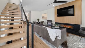 Ein modernes Wohnzimmer mit Treppe, Flachbildfernseher, Kamin und Essbereich.