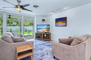 A living room with a TV, two sofas, a coffee table, and a ceiling fan. - Coastal Escape Near Beaches & Downtown (St. Petersburg)