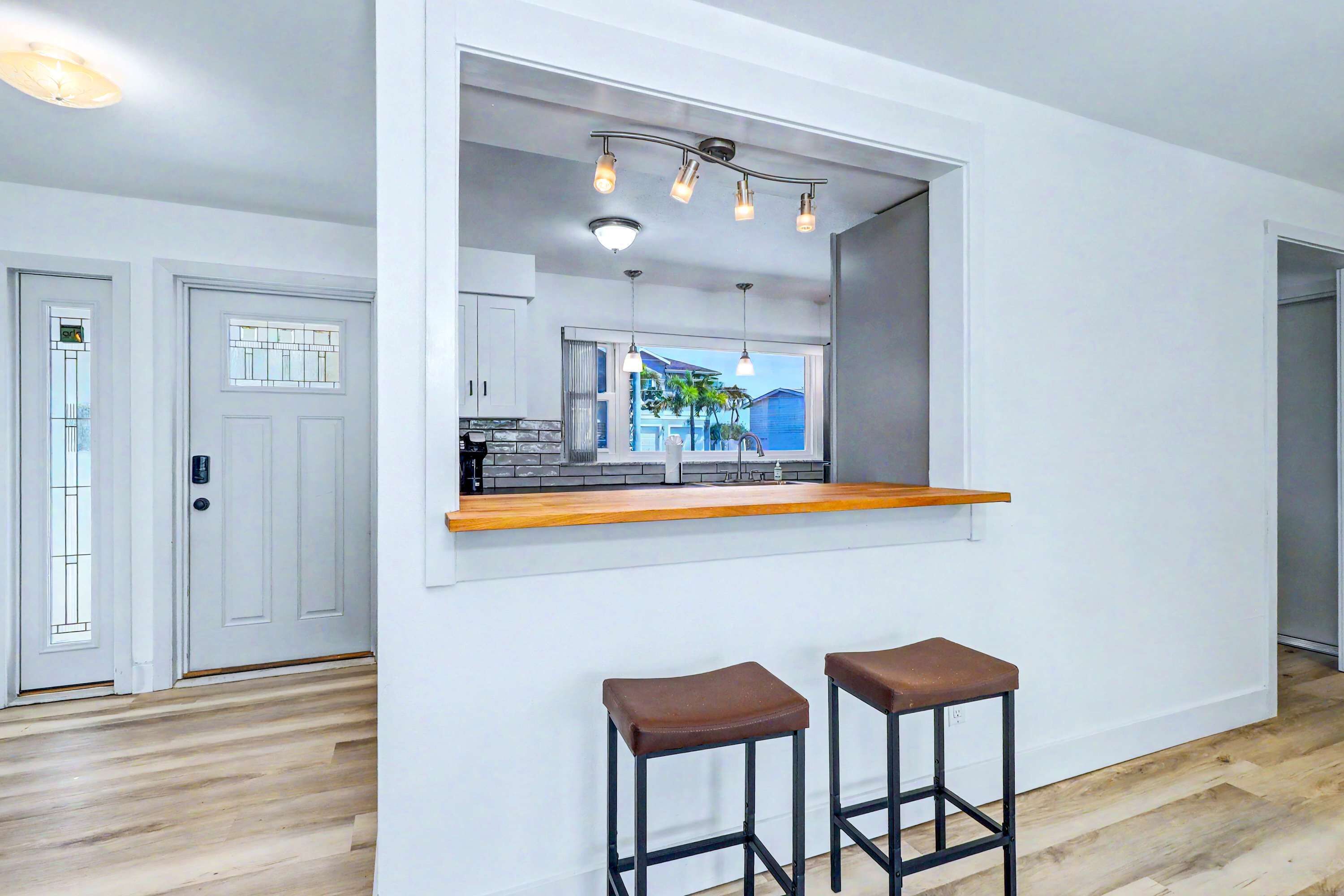 A modern kitchen with a built-in island, two bar stools, and a view of the outside.