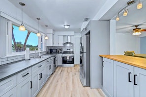 A modern kitchen with stainless steel appliances, white cabinetry, and pendant lighting. - Coastal Escape Near Beaches & Downtown (St. Petersburg)