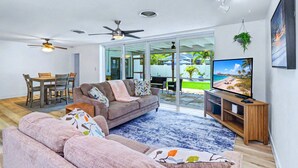 Ein modernes Wohnzimmer mit einer Couch, einem Fernseher und Deckenventilatoren.