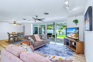 Ein modernes Wohnzimmer mit einer Couch, einem Fernseher und Deckenventilatoren.
