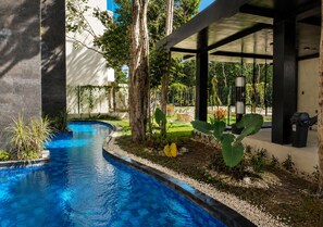 A swimming pool with a tiled edge, surrounded by greenery and a covered area with a trash bin. - Modern Tulum Penthouse ● Private Plunge Pool ● Fast WiFi ● Gym (Tulum)