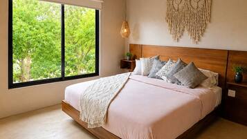 Una camera da letto con un letto, una ventola a soffitto, un'ampia finestra e un elemento decorativo al muro.