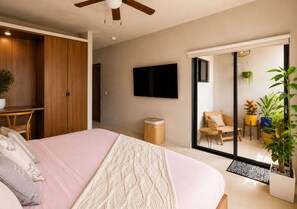A modern bedroom with a bed, a TV, a wardrobe, and a sliding door leading to a balcony with plants. - Modern Tulum Penthouse ● Private Plunge Pool ● Fast WiFi ● Gym (Tulum)