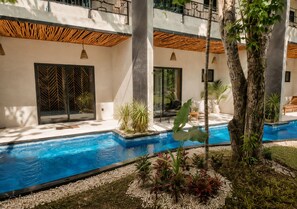 Een modern buitenzwembad met helderblauw water, omringd door beplanting en een terras.
