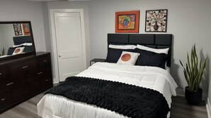 A bedroom with a bed, dresser, mirror, and two wall art pieces. - 2-Car Parking | Private Yard | Near I-95 (Philly) (Chester)