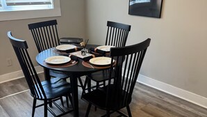 A dining area with a round table surrounded by six black chairs, a vase with flowers, and a framed picture on the wall. - 2-Car Parking | Private Yard | Near I-95 (Philly) (Chester)