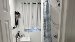A narrow bathroom with a toilet, sink, and shower area. - 2-Car Parking | Private Yard | Near I-95 (Philly) (Chester)
