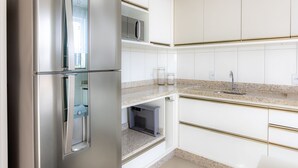 Una cocina moderna con armarios blancos, un refrigerador de acero inoxidable y una encimera de granito.