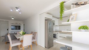 Una cocina moderna con refrigerador integrado, muebles blancos y un comedor con mesa y sillas.