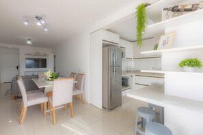 Una cocina moderna con refrigerador integrado, muebles blancos y un comedor con mesa y sillas.