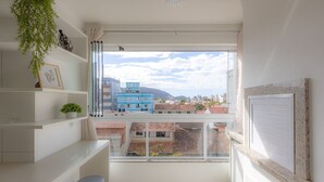 Un balcón con vistas a edificios, una planta y un cuadro enmarcado.