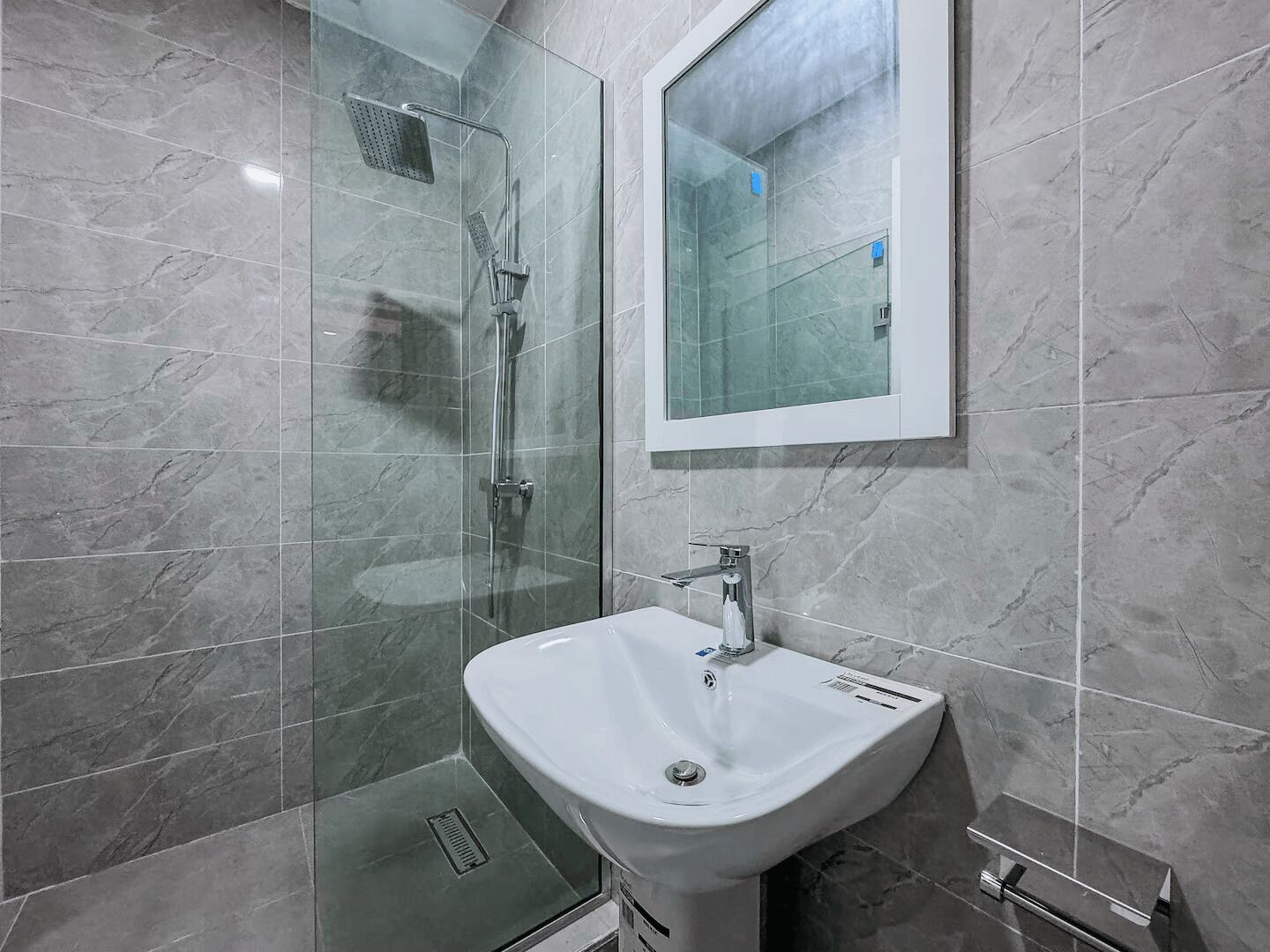 Une salle de bain moderne avec une douche à parois de verre, un lavabo blanc et un miroir.