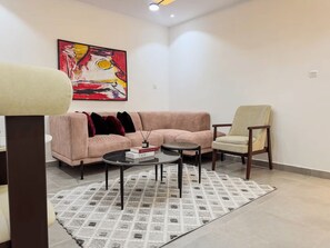 Ein modernes Wohnzimmer mit Sofa, Sessel, Couchtisch und Teppich.