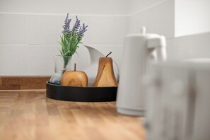 A kitchen counter with a black tray holding a wooden apple and a pear, a glass vase with lavender, and a white mug. - Spacious Home, Sleeps 12, Great Transport Links (Southall)