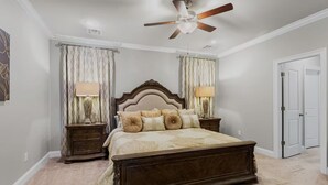 Ein Schlafzimmer mit einem großen Bett, zwei Nachttischen, einem Deckenventilator und einer Tür.