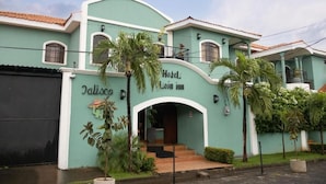 A hotel with a curved entrance, palm trees, and a sign reading 'Hotel Leom inn.' - HOTEL LEON INN (León)