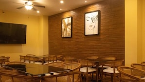 A conference room with a brick wall, framed artwork, and wicker chairs. - HOTEL LEON INN (León)