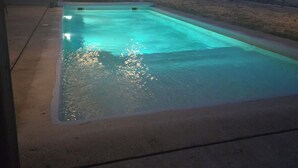 Ein rechteckiger Swimmingpool mit Betonrand, umgeben von einer Betonplattform.