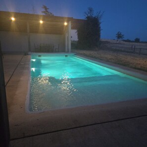 Ein rechteckiger Swimmingpool mit Betonrand, umgeben von einer Betonplattform.