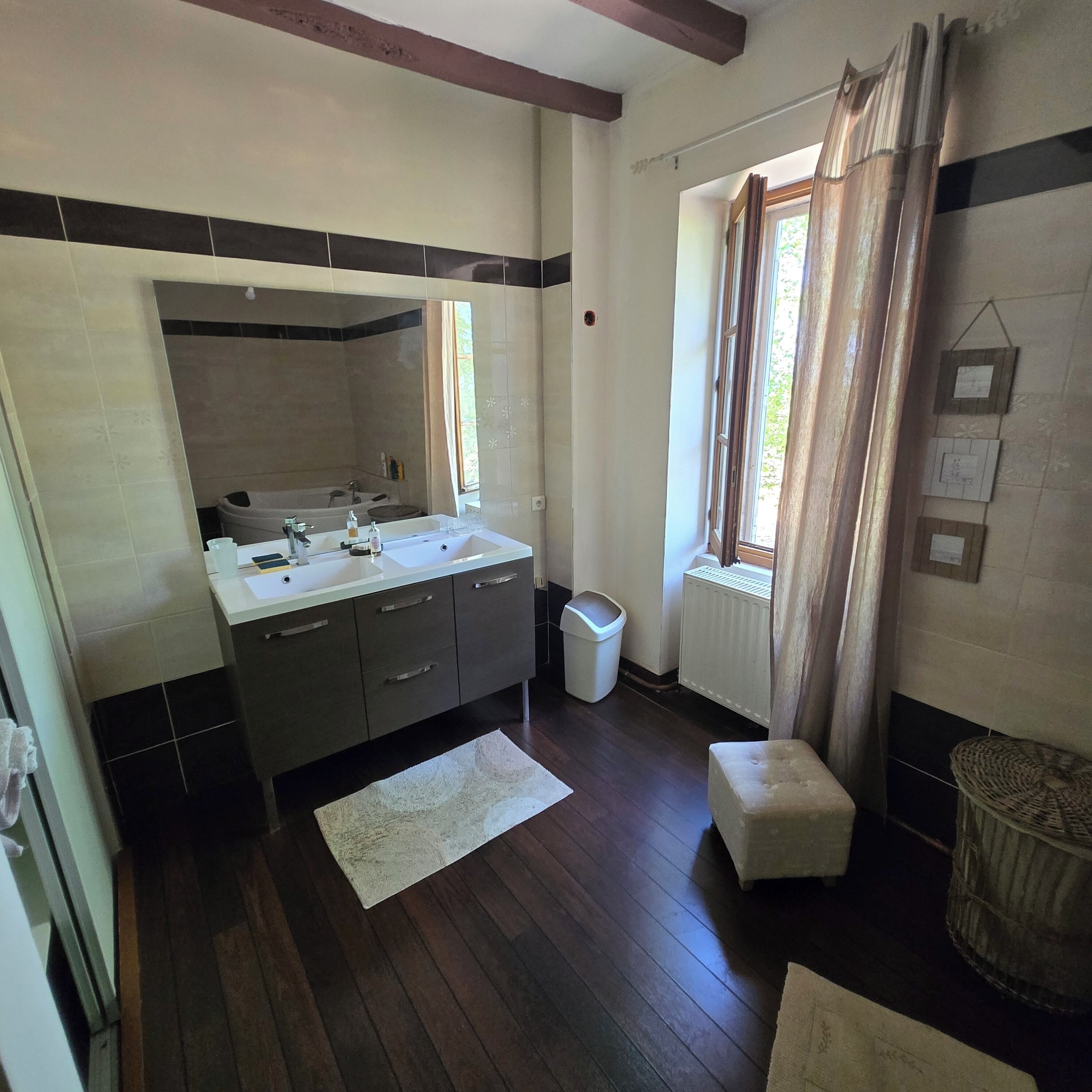 Un baño con bañera, lavamanos y ventana con cortinas.
