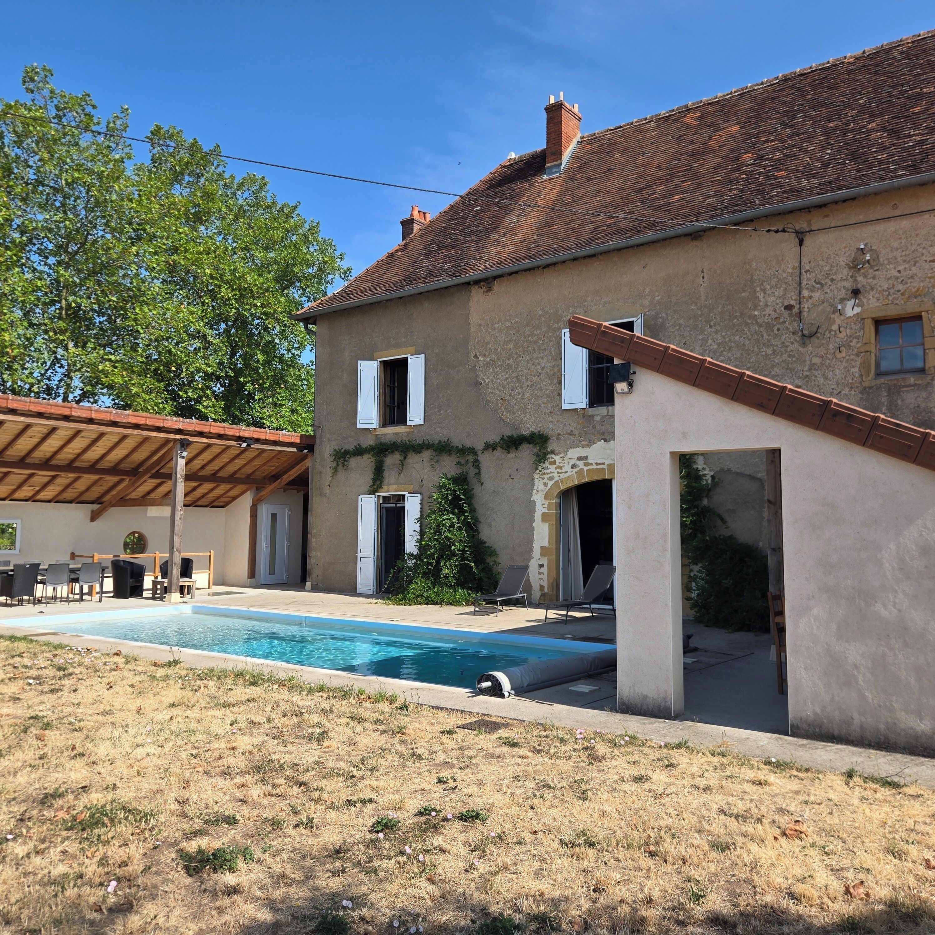 A house with a swimming pool, outdoor seating, and a covered patio area.