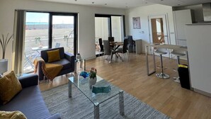 Een moderne woonkamer met een bank, salontafel en een eethoek met stoelen.