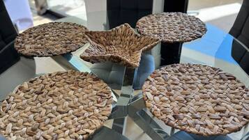 Un comedor moderno con una mesa de vidrio rodeada de sillas negras, con individuales tejidos.