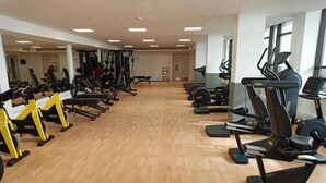 Een sportschool met diverse fitnessapparaten, waaronder loopbanden en krachtapparaten, gerangschikt in rijen.