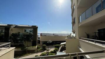 A modern building with a balcony, a clear sky, and a sun shining.