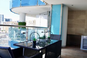 Ein Balkon mit Glastisch und Stühlen, Blumentöpfen und Blick auf die Stadt.