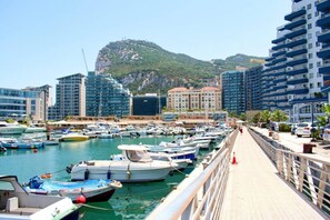 A marina with boats docked, a pedestrian walkway, and buildings in the background. - Gibraltar Luxury w/ Rooftop Pools & Views (Gibraltar)