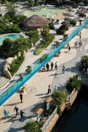 Ein Resort mit Poolbereich, Spazierwegen und Liegestühlen.