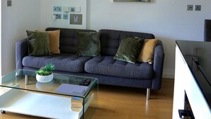 A modern living room with a sofa, a glass coffee table, and a painting on the wall. - Gibraltar Luxury w/ Rooftop Pools & Views (Gibraltar)