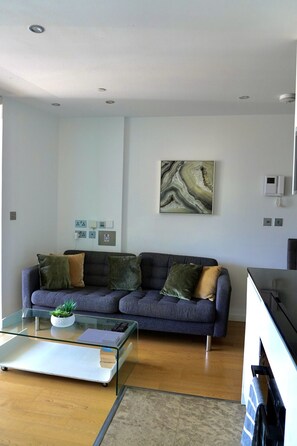 A modern living room with a sofa, a glass coffee table, and a painting on the wall. - Gibraltar Luxury w/ Rooftop Pools & Views (Gibraltar)